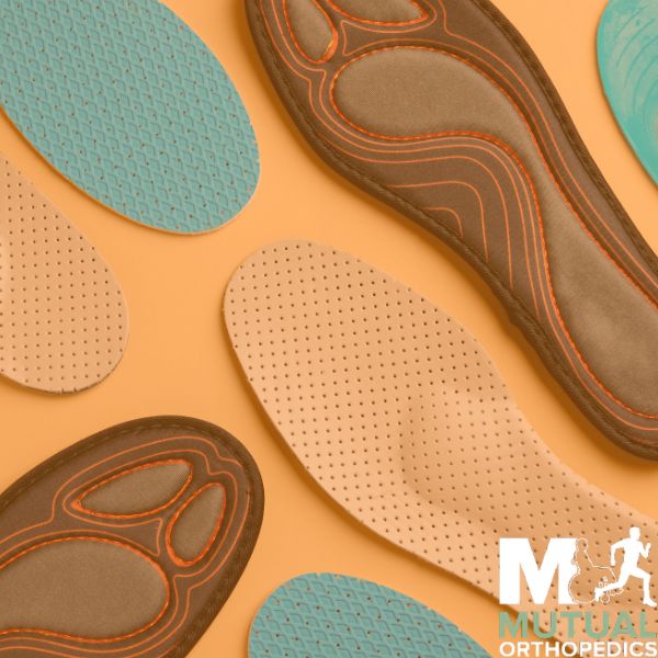 Assorted orthopedic insoles in different shapes and colors are displayed on a light orange background with a Mutual Orthopedics logo in the corner 