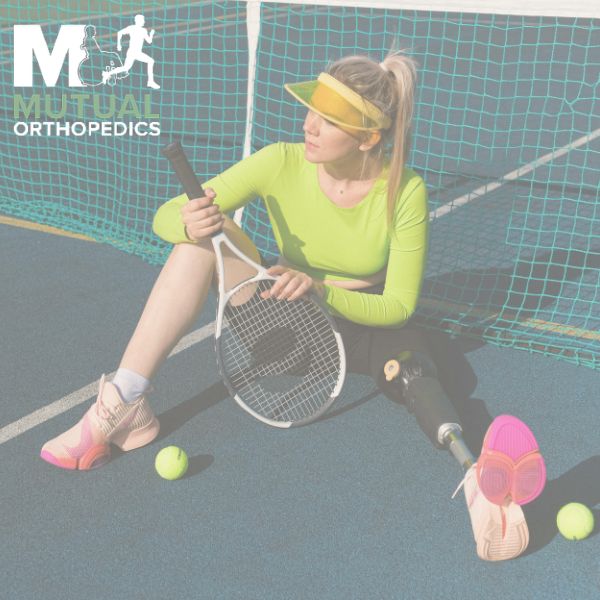 A woman with a prosthetic leg sits on a tennis court with a racket and tennis balls, wearing a visor and neon sportswear "Mutual Orthopedics" logo is visible in the corner